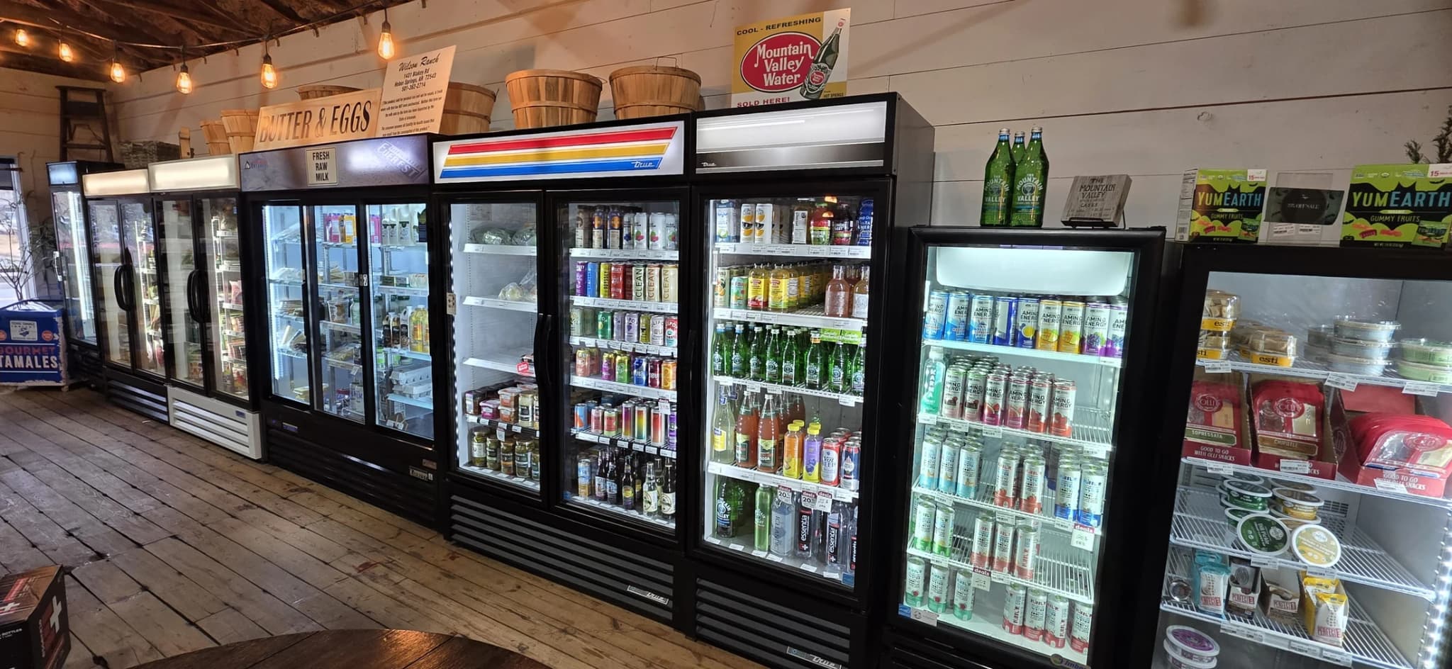 A row of glass-door coolers stocked with chilled drinks, dairy, and grab-and-go groceries