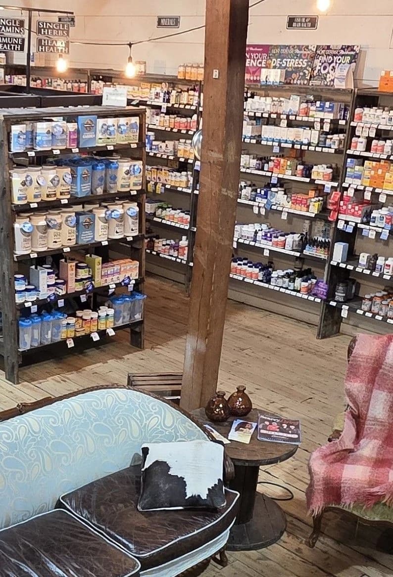 Aisles of vitamins and supplements inside the Natural Food Store, with a paisley sofa and armchair in the foreground